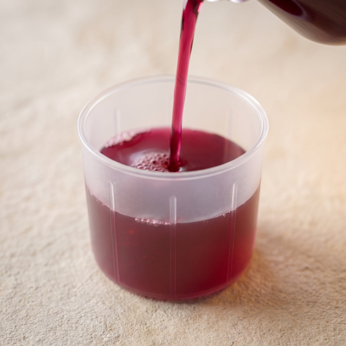 Liquide rouge fruits rouges versé dans le doseur translucide